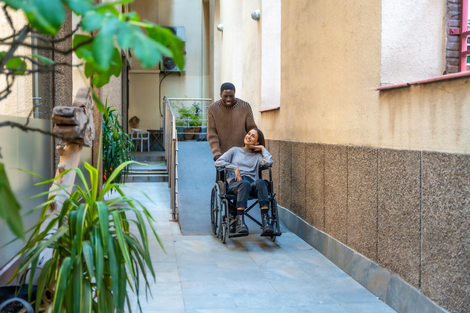 Un hombre empuja a una mujer en silla de rudas por una rampa gracias al proyecto de accesibilidad